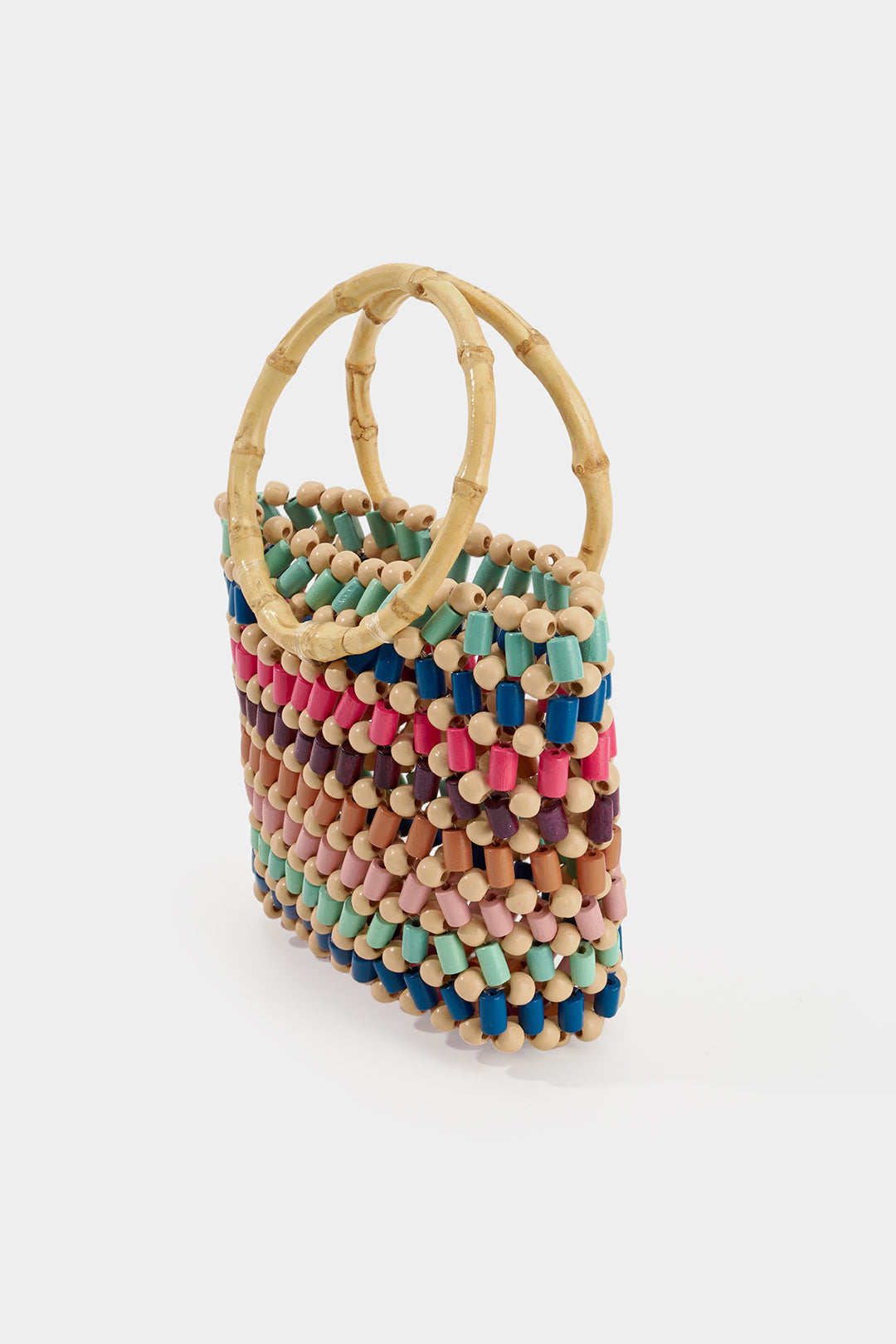 A small woven handbag with natural bamboo handles and a colorful striped body made of wooden beads in pink, blue, teal, brown, and beige, set against a plain light gray background.